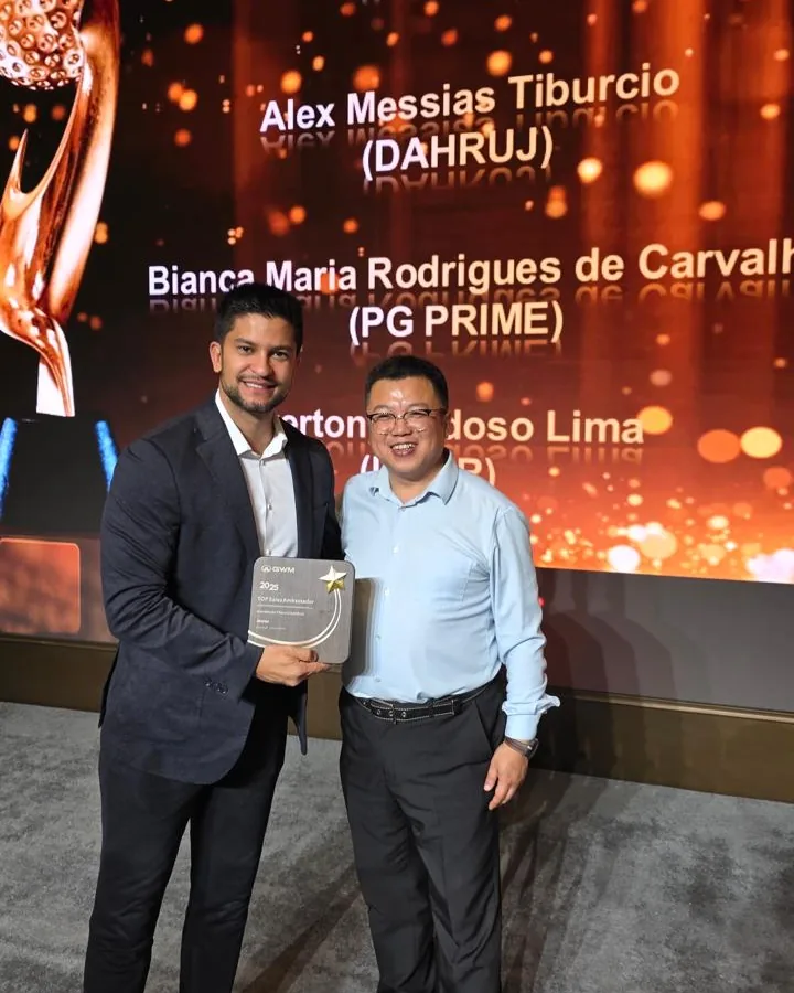 Alex Messias recebendo o prêmio TOP Sales Ambassador da GWM no palco, com seu nome no telão